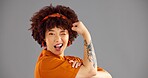 Portrait, flexing arms and woman with wink, smile and space with confident personality on grey background. Face, happy person or model with gesture, strong or female empowerment with challenge or win