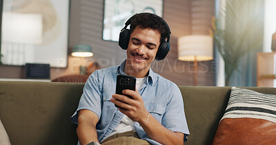 Buy stock photo Headphones, man and relax with phone in home for streaming service, watching online video or weekend break. Happy, person and smartphone on sofa for audio playlist, music album or internet connection