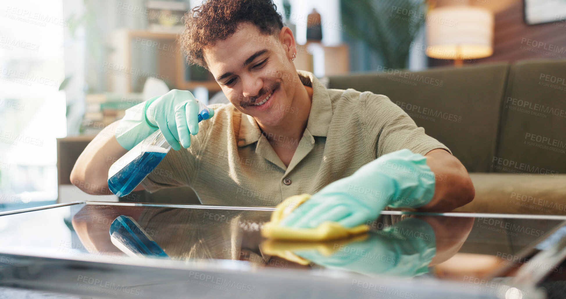 Buy stock photo Happy man, spray bottle and table with detergent for cleaning service or housekeeping at home. Male person, maid or cleaner with smile, gloves or cloth for bacteria or germ removal on glass surface