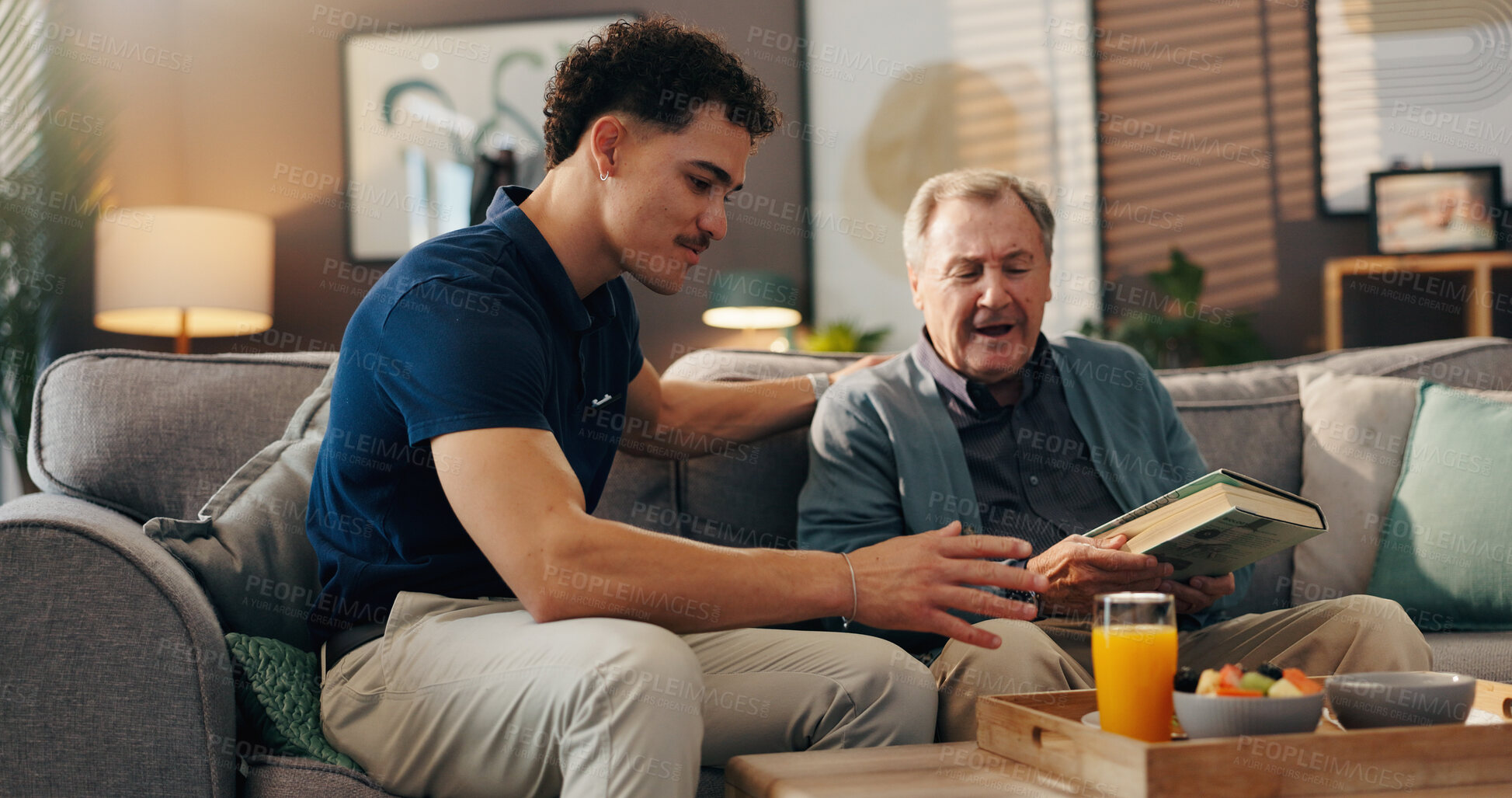 Buy stock photo Caregiver, elderly man and breakfast on sofa, reading or talk with book, food or nutrition in lounge. Male nurse, senior patient and smile for meal with diet, advice and literature in retirement home