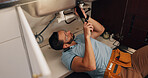 Man, plumber and repair in kitchen, pipe and sink with search for leak, problem solving and assessment in home. Person, handyman and tools for job, drain and solution for maintenance at apartment