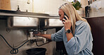 Woman, phone call and stress by kitchen sink in home, emergency and talking for leak with pipe. Person, smartphone and contact for repair, help and plumbing services for drain in morning at house