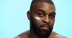 Portrait, cream and black man with cosmetics, skincare and dermatology on blue studio background. African person, space and model with shine, creme and glow with moisturiser, beauty and facial spf