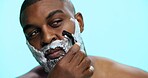 Razor, foam and shaving with black man in studio, cosmetic care and product with skincare on blue background. Soap, cream or facial maintenance for hair removal, shaver or grooming for hygiene