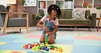 Child, block and building with toys for fun activity or playing on floor at elementary school. Black girl, kid or student with shapes for playful learning, fine motor skills or education in classroom