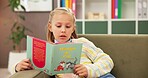 Girl, reading and sofa with book for learning, education or lesson at private elementary school. Child, kid or student with novel on couch for early childhood development, knowledge or story time