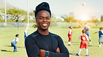 Portrait, coach and man with arms crossed, soccer and confident for training routine, happy or outdoor. Sports field, trainer and person with smile in morning, proud and fitness for football or match