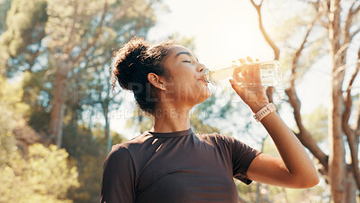 Buy stock photo Woman, drinking water and fitness in nature for hydration, electrolytes and body detox. Low angle, runner and thirsty in forest with H2O, exercise break and liquid for gut health with digestion aid