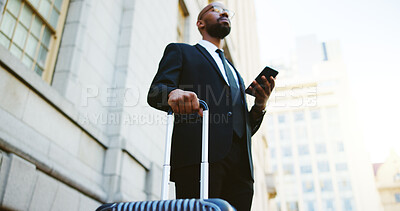 Buy stock photo Suitcase, travel and black man in city with cellphone for communication, contact or email. Phone, corporate trip and African male finance manager with business networking in urban town from low angle