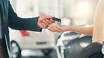 Car showroom, salesman and customer with hands for keys, test drive or success purchase of motor. Dealership, people or giving equipment in closeup for buying vehicle, rental service or auto by flare