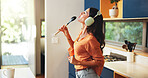 Woman, music and singing with headphones in kitchen for audio playlist, weekend entertainment and radio sound. Fun, person and karaoke with spoon in home for online song, listening to album and relax