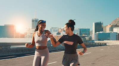 Buy stock photo Happy women, fitness or running with fist bump in city for workout motivation or success. Active, female people or runners with smile or touch for cardio training, sprint or exercise together in town