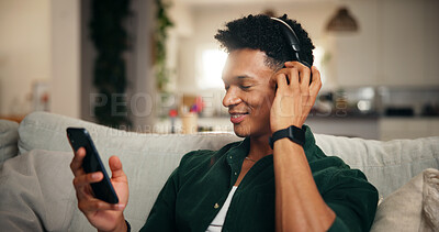 Buy stock photo Headphones, smile and phone with man on sofa for social media, movie platform and streaming service. Happiness, entertainment app and subscription with person in living room at home for multimedia
