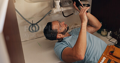 Buy stock photo Man, plumber and tools for kitchen sink, pipe and search for leak, problem solving and fix in home. Person, handyman and check for water, drain and solution on floor for maintenance at apartment