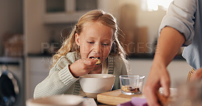 Buy stock photo Girl, child and eating in kitchen, cereal and hungry with parent for diet, bonding and care in house. People, kid and food in morning with nutrition, healthy meal or routine with love in family home