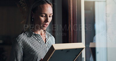 Buy stock photo Woman, photo frame and sad by window with memory, mourning and regret or loss of loved one at home. Female person, widow and picture with sorrow at house with nostalgia, lonely and reflection