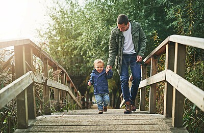 Walking, bridge and father holding hands with child for playing, explore and adventure for fun outdoors. Childhood, nature and dad with young boy for journey bonding on vacation, holiday and weekend