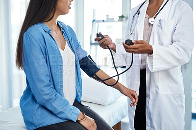 Buy stock photo Shot of a young woman getting her blood pressure measured during a checkup with a doctor