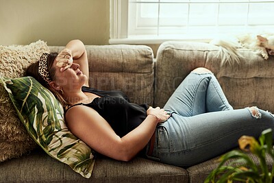 Buy stock photo Period pain, menstruation and a woman on a sofa in the living room of her home suffering from cramps. Stomach, digestion and constipation with a young female person holding her belly in discomfort