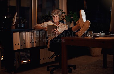 Buy stock photo Business, tablet and mature woman at desk with relax for notification, reading proposal or review. Night, online and employee with technology for information, email or news article in home office