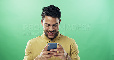 Buy stock photo Man, phone and happy with texting in studio with notification, meme and laugh by green background. Person, smile and scroll with smartphone on mobile app, mockup space and funny video on social media