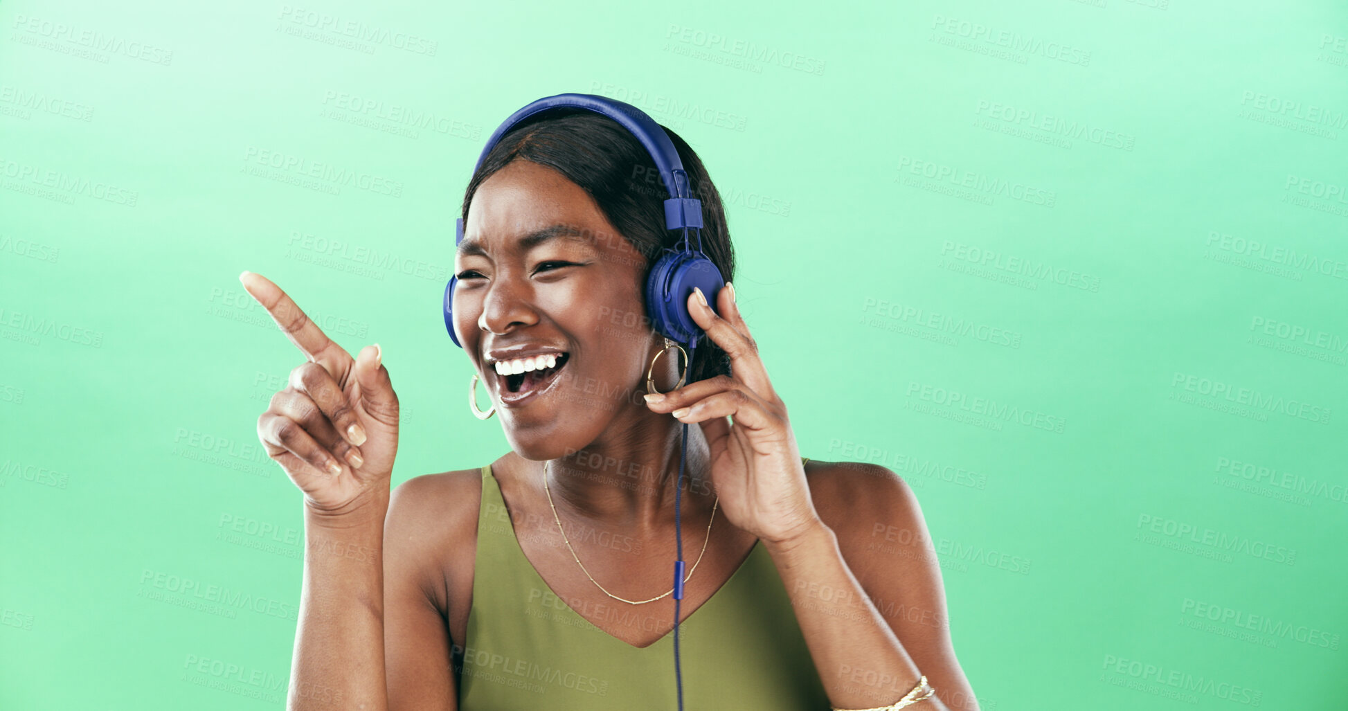 Buy stock photo Music, dancer and headphones with black woman in studio for streaming, audio playlist and song. Pointing, sound and dancing with female person listening on green background for entertainment or space