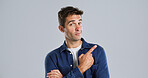 Pointing, portrait and man in studio, promotion and announcement on gray background. Person, mockup space and model with hand gesture, choice and discount deal with sales, decision and confidence