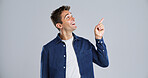 Pointing, smile and man in studio, promotion and opportunity on gray background. Happy person, mockup space and model with hand gesture, choice and discount deal with sales, decision and excited