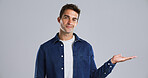 Happy man, portrait and hand out with advertising in studio for marketing on a gray background. Male person, model or smile with palm or deal for notification, alert or promotion on mockup space