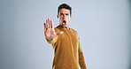 Warning, stop and portrait of man in studio for rejection, deny or no hand gesture for protest. Shout, serious and male person with palm for caution, safety or self defense by gray background.