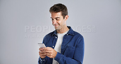 Buy stock photo Smile, phone and man in studio for typing, text or reading message on white background space. Mobile, happy person or check email online on app for notification, play game or social media on internet