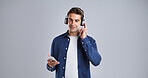 Man, phone and listen with headphones in studio for streaming music, radio and playlist. Mockup space, male person or mobile for hearing song, groovy audio and online subscription on white background
