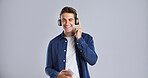 Headphones, happy and man with phone in studio listening to music, playlist or album on mobile app. Smile, audio tech and male person with cellphone for streaming song online by white background.