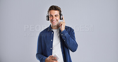 Buy stock photo Headphones, happy and man with phone in studio listening to music, playlist or album on mobile app. Portrait, audio tech and person with cellphone for streaming song online by white background space