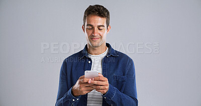 Buy stock photo Smile, mobile and man in studio for text, typing or reading message on white background. Phone, happy person and check email online on app for forum post, response or social media with mockup space