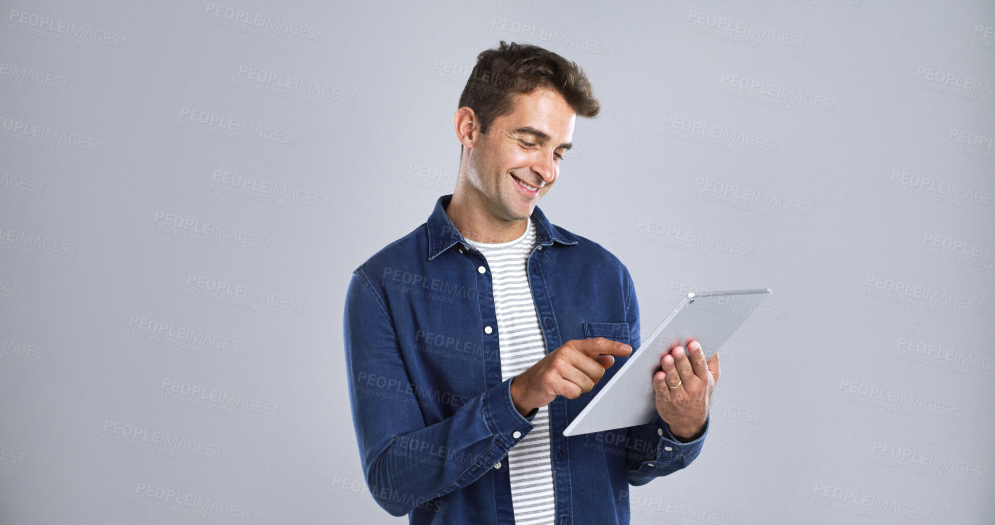 Buy stock photo Man, smile and scroll on tablet in studio for connection, internet or network on white background. Digital technology, mockup space and happy male person with touchscreen for social media or website 