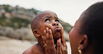 Black family, child and beach with mother for sunscreen, safety or outdoor UV protection in nature. Kid, son and mom with face for SPF, skincare or love together for childhood on ocean coast or sea