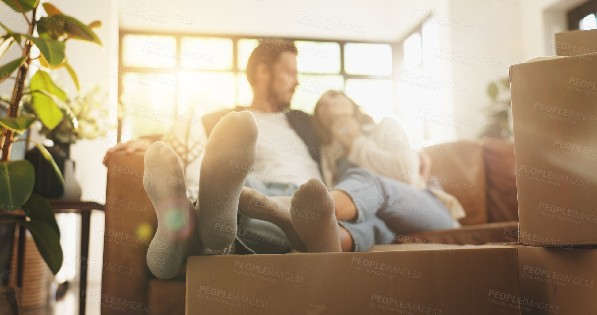 Buy stock photo Couple, relax and feet with boxes at new house for relocation, investment and bonding together. People, lens flare and couch for moving property, loan success and relationship commitment of ownership