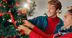 Christmas, home and couple with tree, tradition and bonding together with love, romance and smile. Interracial, relationship and man with woman, Xmas and marriage with celebration and festive season