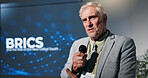 Mature, businessman and presentation with mic at seminar for discussion on global organization. Man, speaker or executive for government speech for BRICS convention or tradeshow at corporate summit