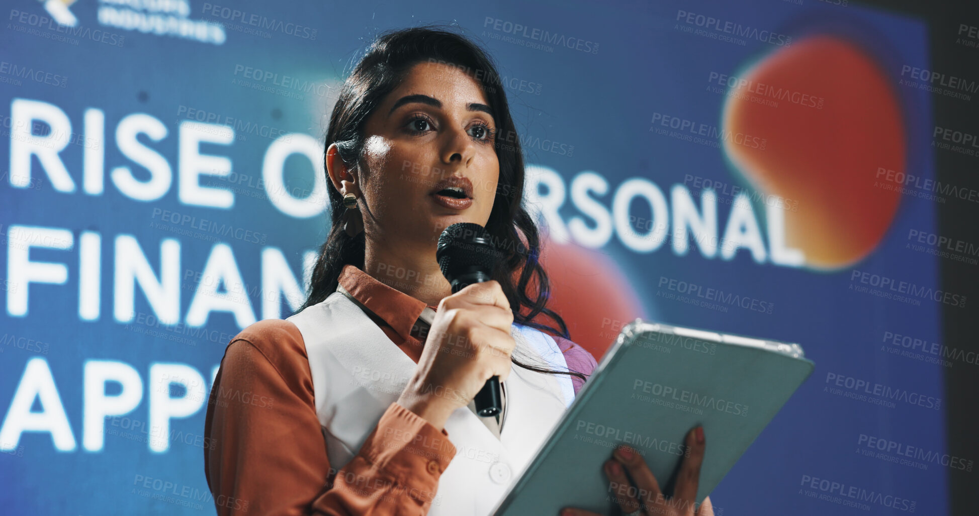 Buy stock photo Presentation, speech and tablet with business woman at symposium for financial development. App, event and stage with Indian speaker in auditorium for introduction to personal finance solutions