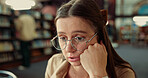 Girl, student and stress with glasses in library for difficult lesson, exam preparation or deadline. Female person, academic or nerd with anxiety or confused for information or studying at university