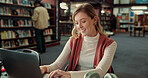 Learning, happy woman and typing on laptop in library for education or notes revision in college. University student, computer and girl on internet to research assignment, study or test preparation