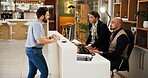 Man, welcome and help desk at hotel with check in, talk and booking info for suite on vacation. People, concierge and client at counter for reservation, discussion and hospitality service at lodge