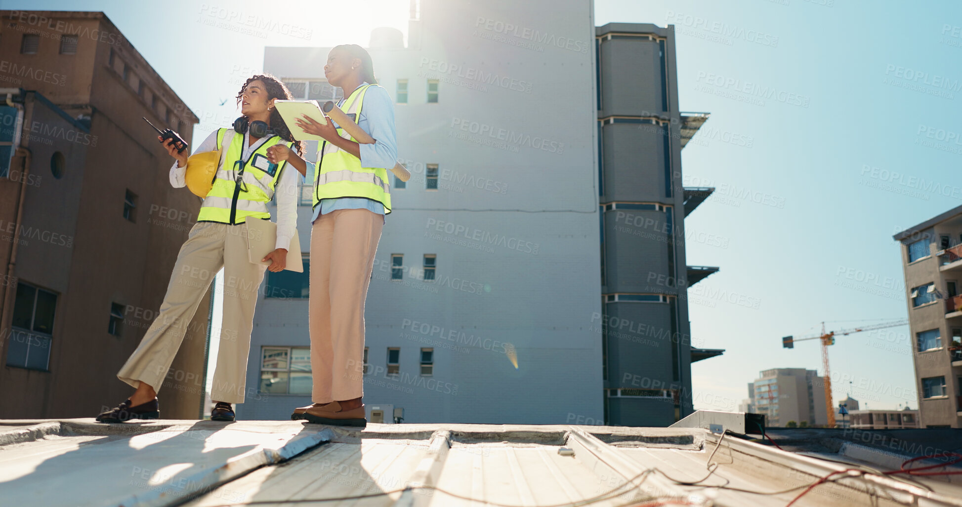 Buy stock photo Women, architecture team and discussion with tablet on construction site, inspection or maintenance. Radio, communication and tech for city planning in low angle, civil engineering and collaboration 