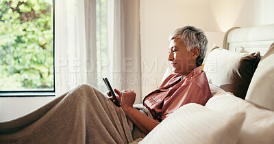 Buy stock photo Phone, scroll and mature woman in bed with dating app, social media or comedy video on internet. Happy, technology and senior female person with smile on cellphone in home for retirement break