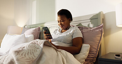 Buy stock photo Reading, phone and relax with black woman in bedroom for chat, notification and morning routine. Smile, social media and wellness with person in home for contact, typing and online news update