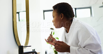 Buy stock photo Jade roller, mirror and black woman in bathroom for skincare, beauty and facial treatment. Dermatology, home and person with face massage for cosmetics, grooming and health for morning routine