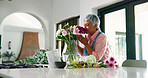 Old woman, smell and flowers in vase at house of special occasion, aesthetic and bloom scent. Senior person, arrangement and plant fragrance of floral bouquet, hospitality decoration and resort setup