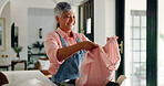 Happy old woman, cleaning and folding laundry in home for housekeeping or hygiene maintenance. Housework, person and fabric in basket for chores, morning routine and organizing clothes in retirement